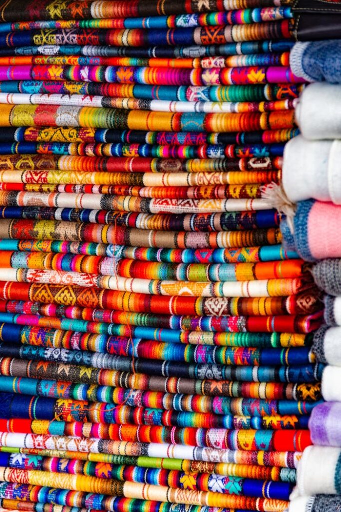 Vibrant multicolored textiles stacked in traditional market display.